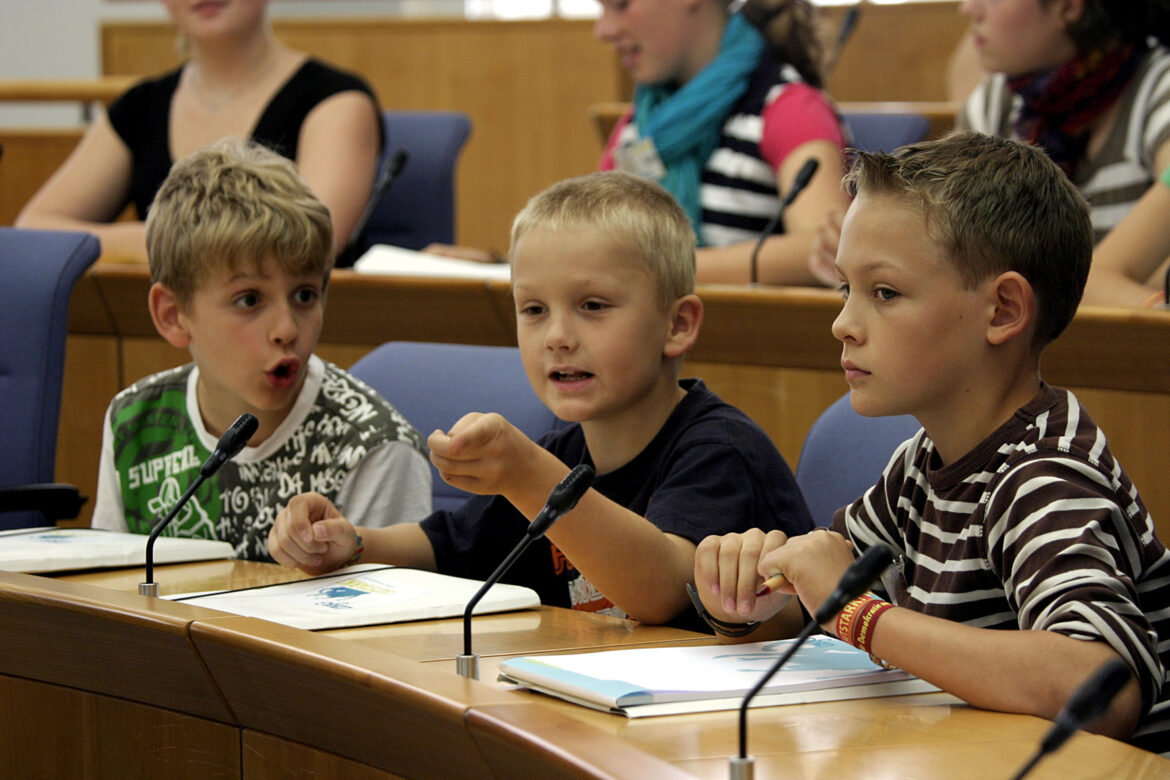 Drei Mädchen und drei Jungen sitzen im Landtag und debattieren