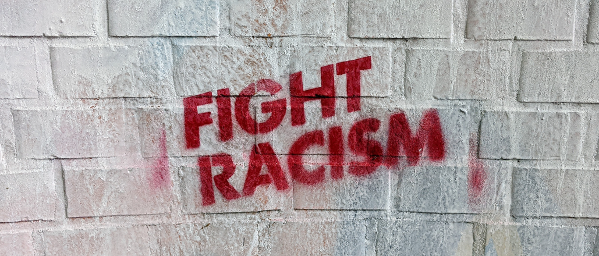 Wand weiße Steine mit rotem Schriftzug fight rassism
